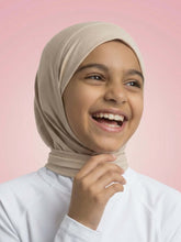 Young girl wearing a beige hijab against a pink background