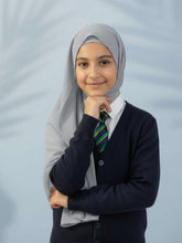 Young girl wearing a hijab, school uniform with a striped tie against a light gray background