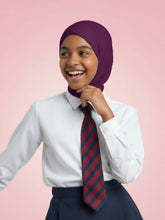 Person wearing a white shirt, navy skirt, and a striped tie with a purple hijab on a pink background