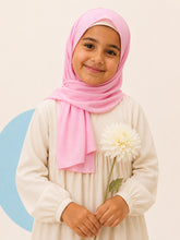 Girl wearing the pink jersey hijab for girls, holding a cream dahlia, front view