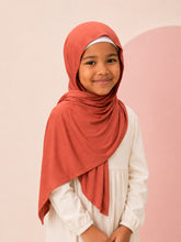 Girl wearing the rust jersey hijab for girls, three quarter front view