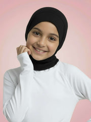 Young girl wearing a black hijab and white turtleneck against a pink background
