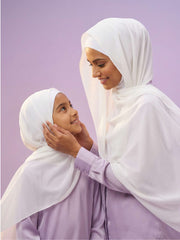 Mom and daughter wearing white bubble girl hijabs against a light purple background