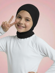 Child wearing a black hijab and white shirt on a pink background