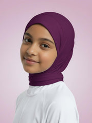 Young girl wearing a purple hijab against a pink background