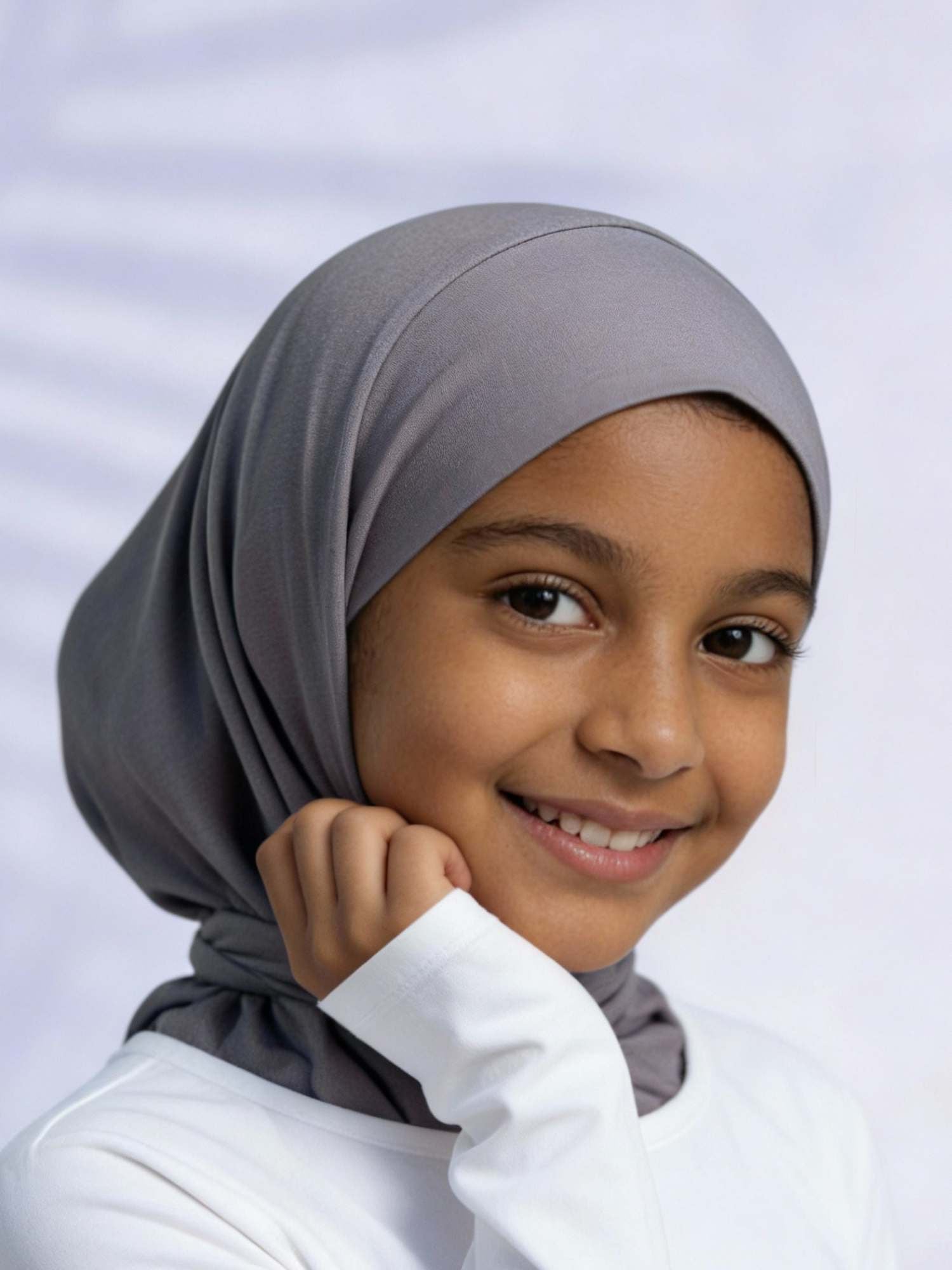 Young girl wearing a gray hijab against a white background