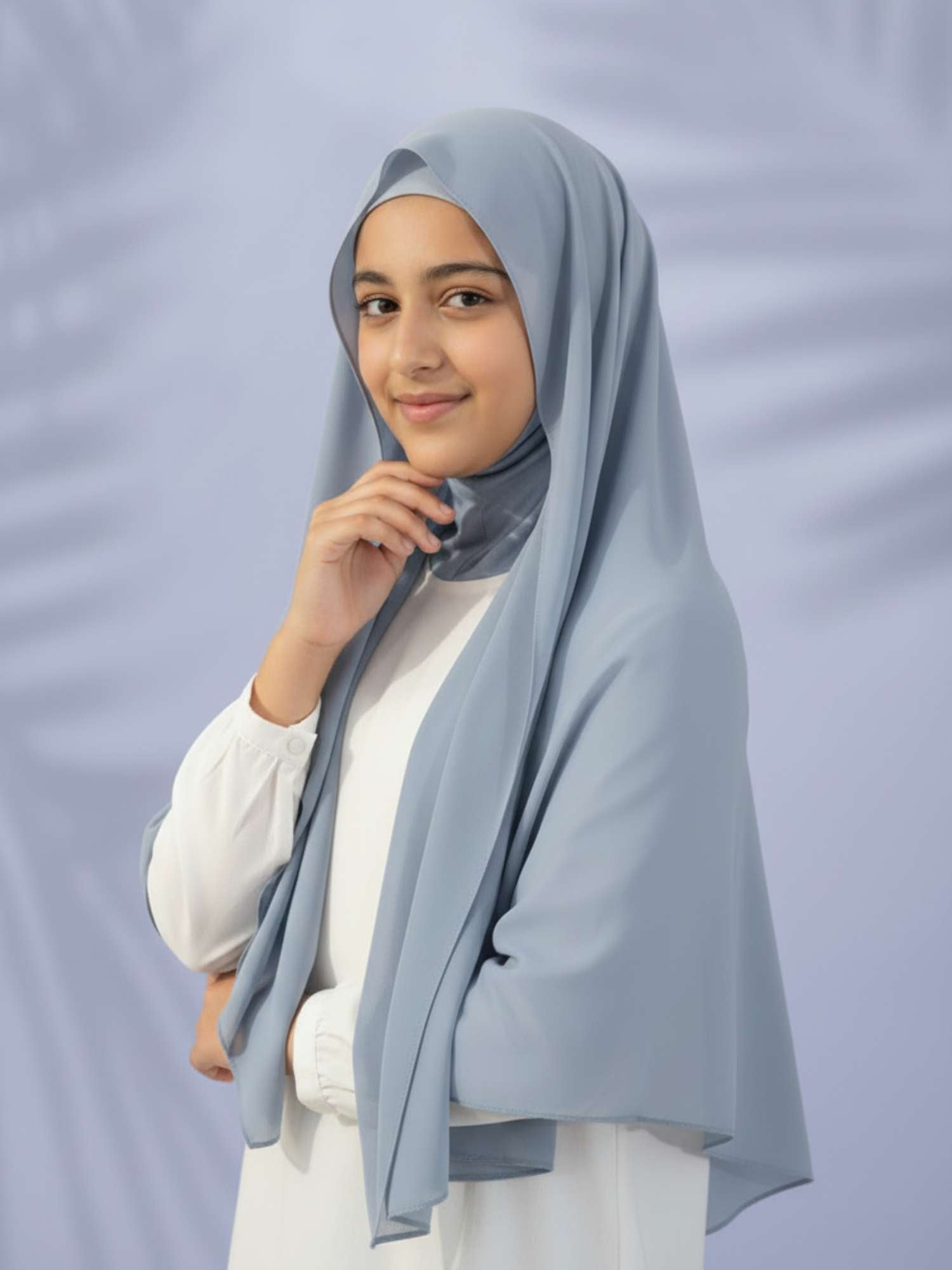 Woman wearing a light gray hijab against a plain background
