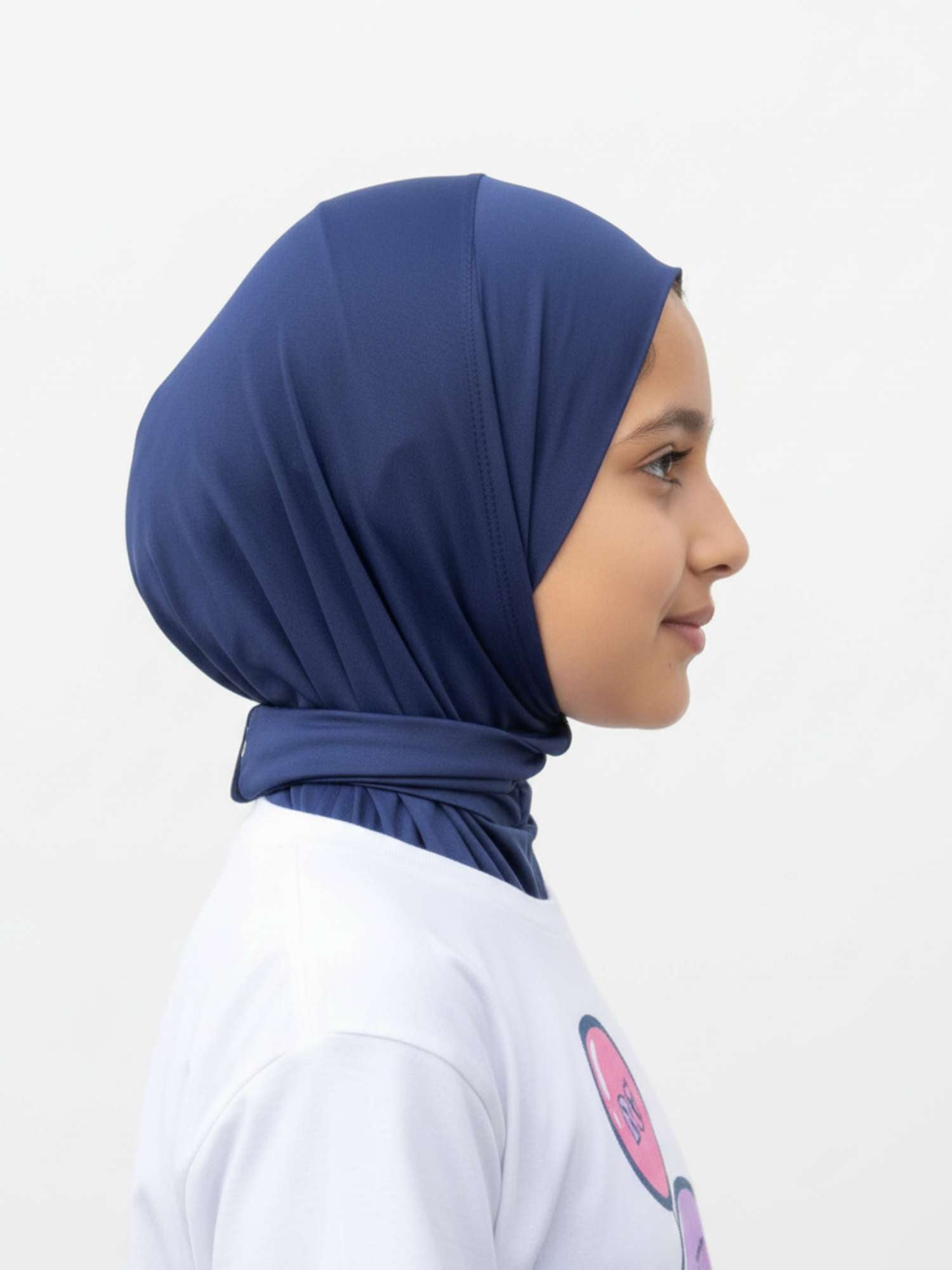 Person wearing a navy blue hijab and a white shirt with a colorful design on a light gray background
