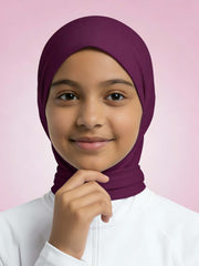 Young girl wearing a purple headscarf against a pink background