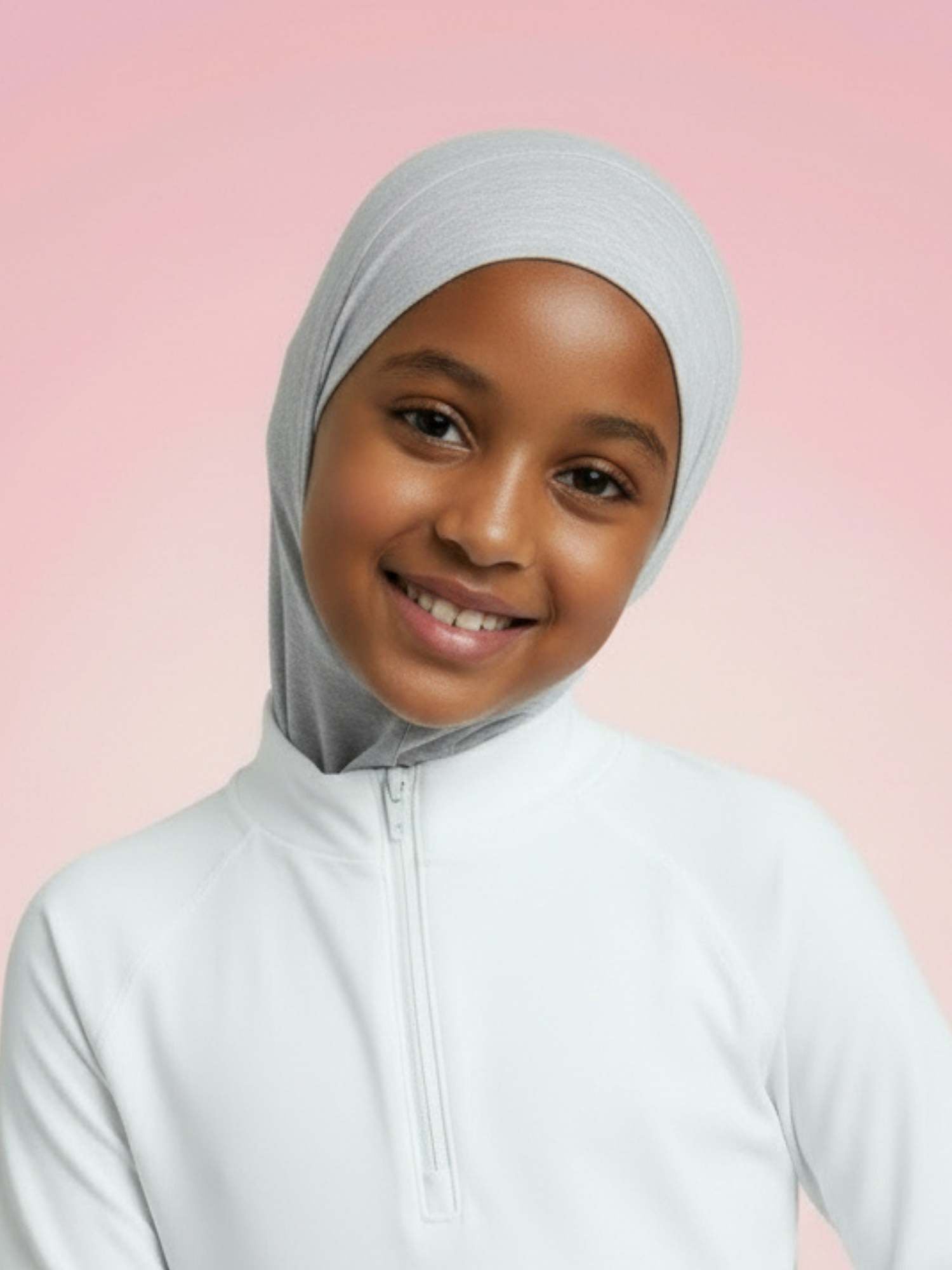 Young Somali girl wearing a gray hijab and white athletic outfit against a pink background