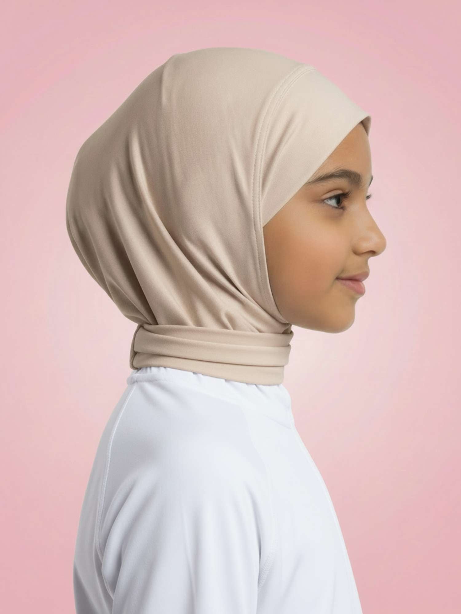 Young girl wearing a beige hijab against a pink background