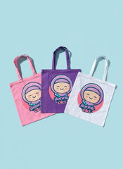 Three cute tote bags in pink, purple, and white with a cartoon character on a light blue background.