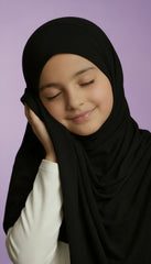 child wearing a black hijab against a purple background