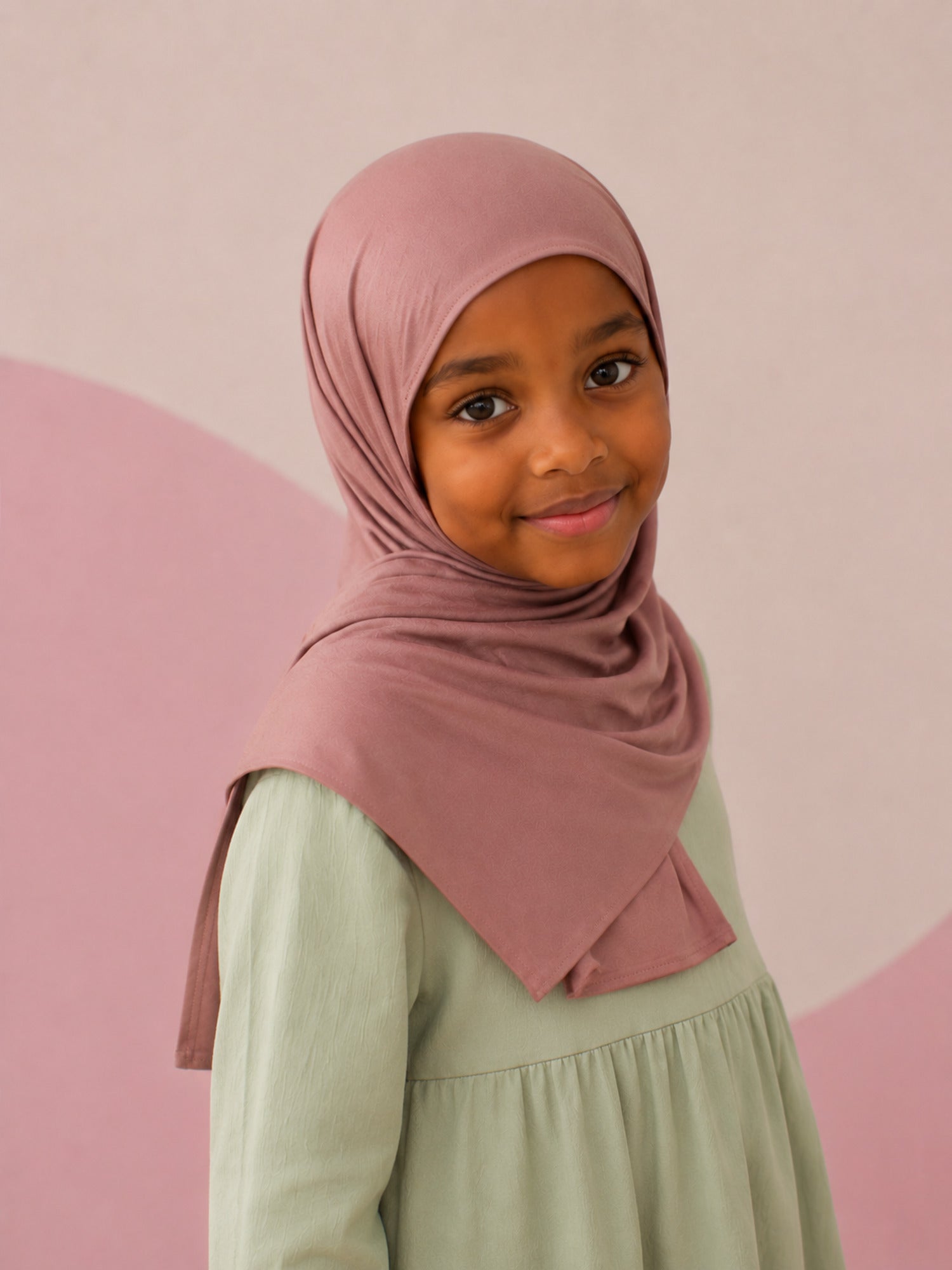 Girl wearing the dusty rose jersey hijab for girls, three quarter front view