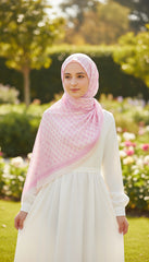 Woman wearing a pink hijab and white dress in a garden setting