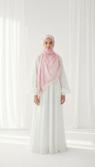 Woman wearing a white dress and pink hijab in a bright room with white curtains.