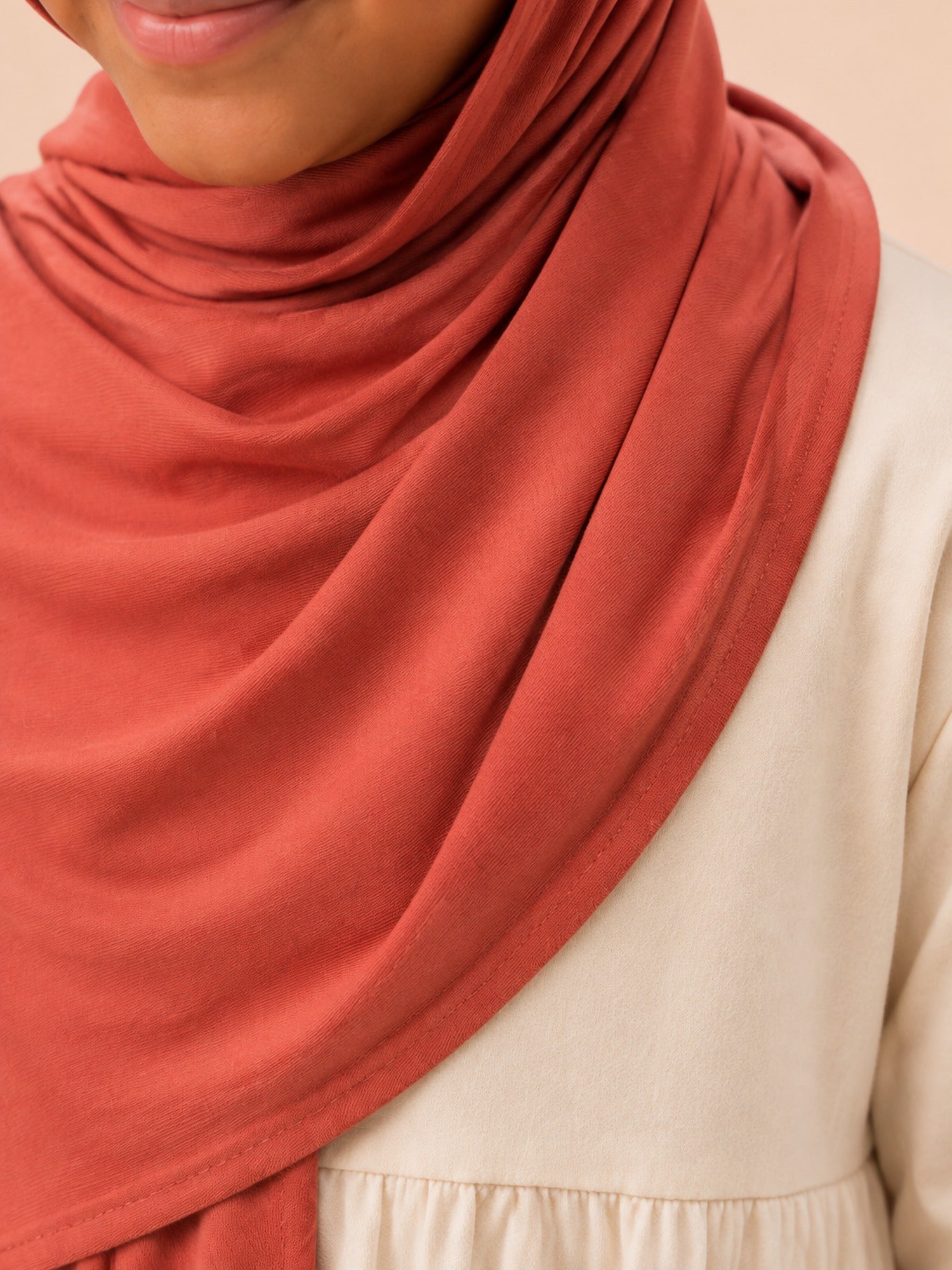 Close up of the rust jersey hijab fabric draped across the shoulder