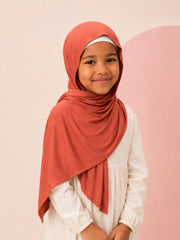 Girl wearing the rust jersey hijab for girls, three quarter front view