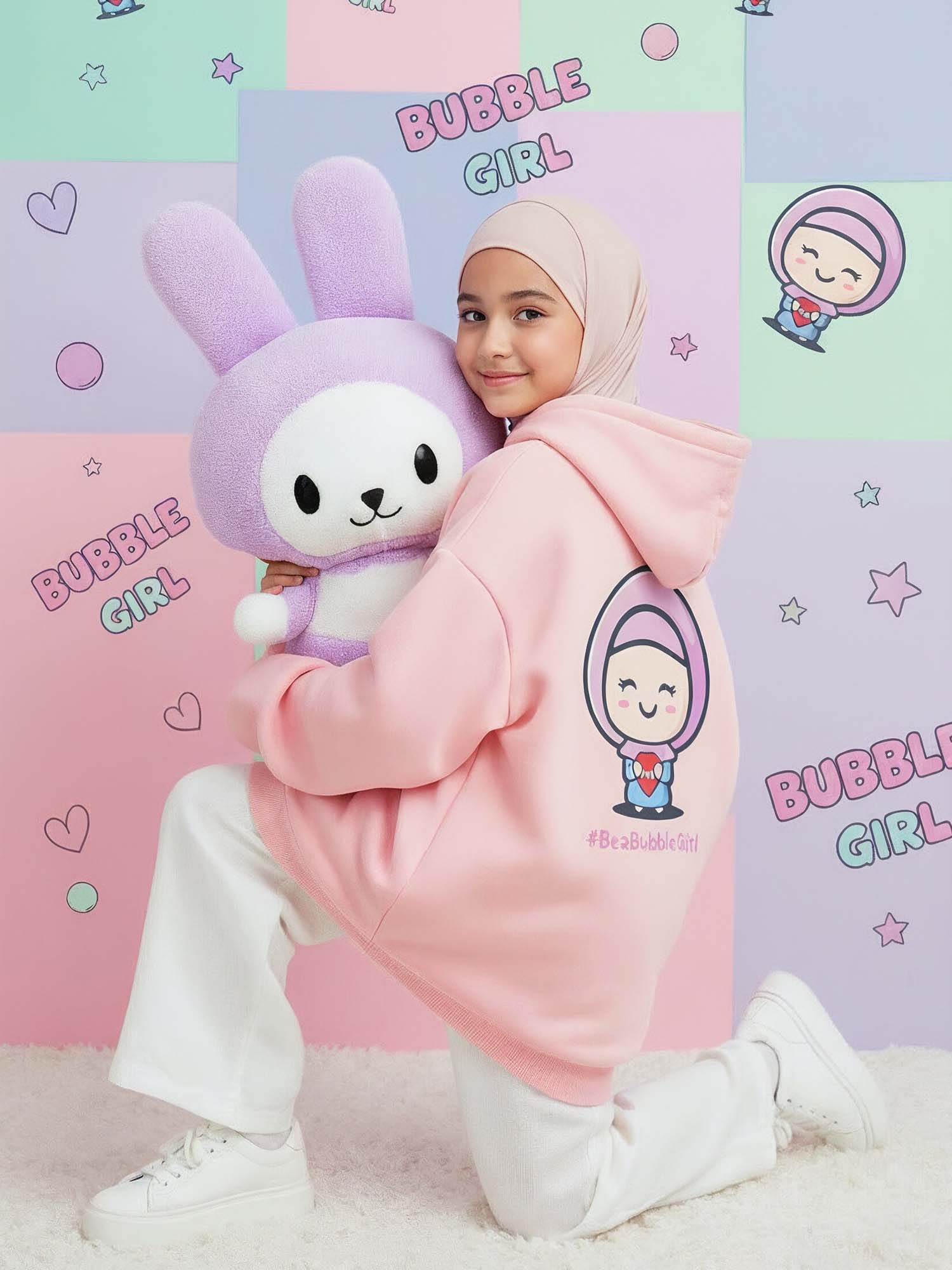 cute girl wearing a pink hoodie dress with a cartoon character, holding a plush toy, against a colorful 'Bubble Girl' themed background.