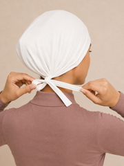 White jersey tie-back undercap, back view showing the adjustable fabric ties tied at the nape