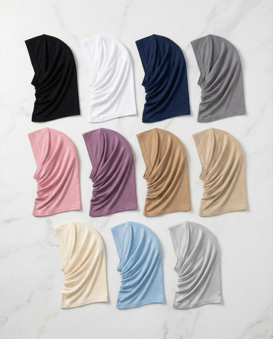Flat lay of FitWrap instant sports hijabs for girls in twelve colours including black, navy, white and grey