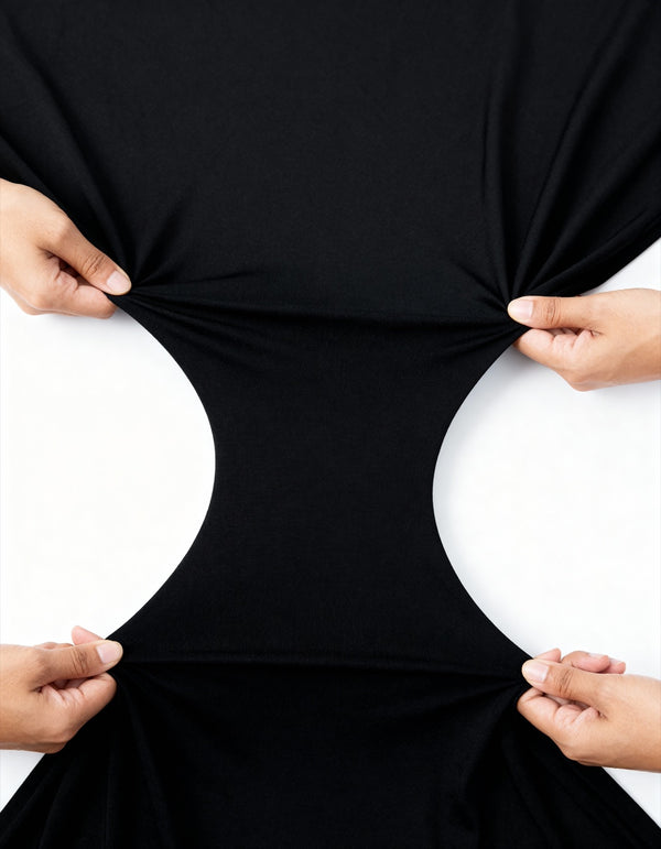 Hands stretching the black FitWrap cotton jersey wide to show its four-way stretch